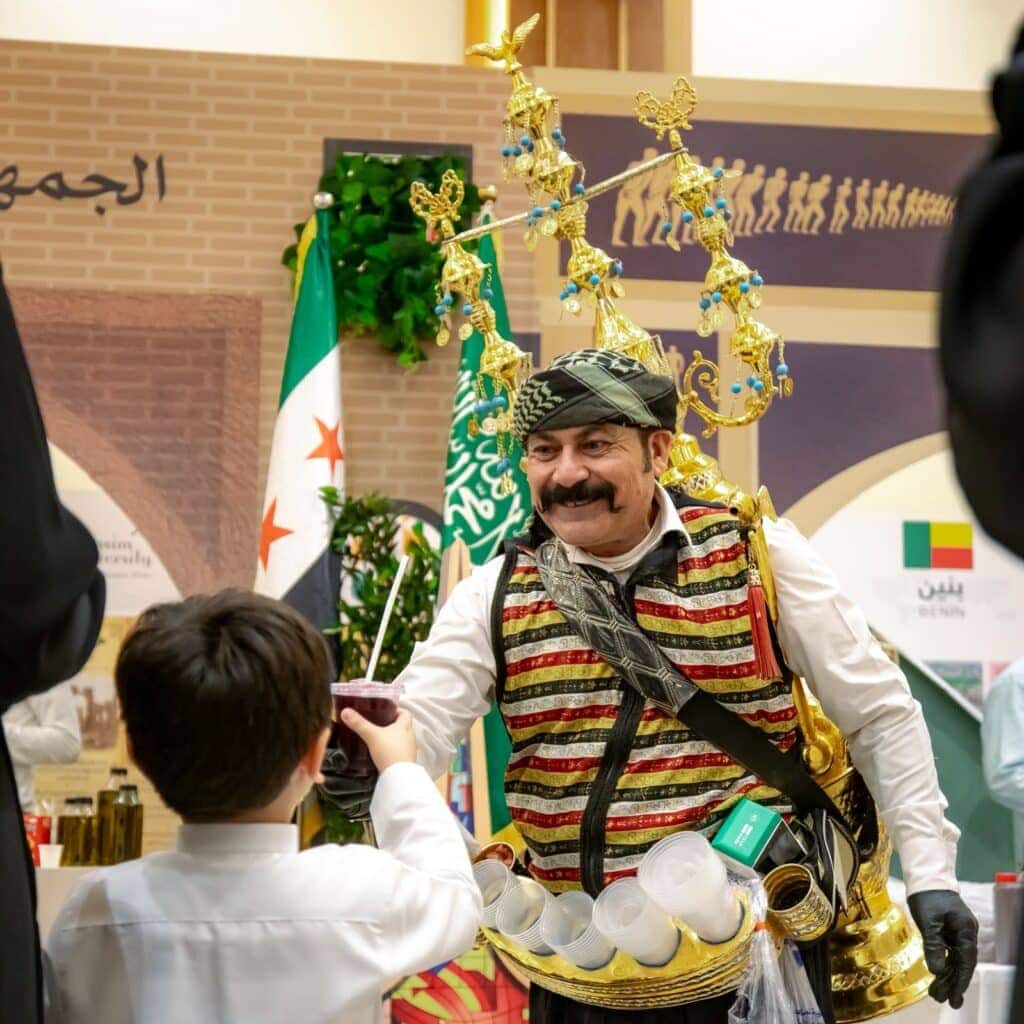 A tea seller at the Qassim University festival offers hospitality to visitors as part of heritage activities.