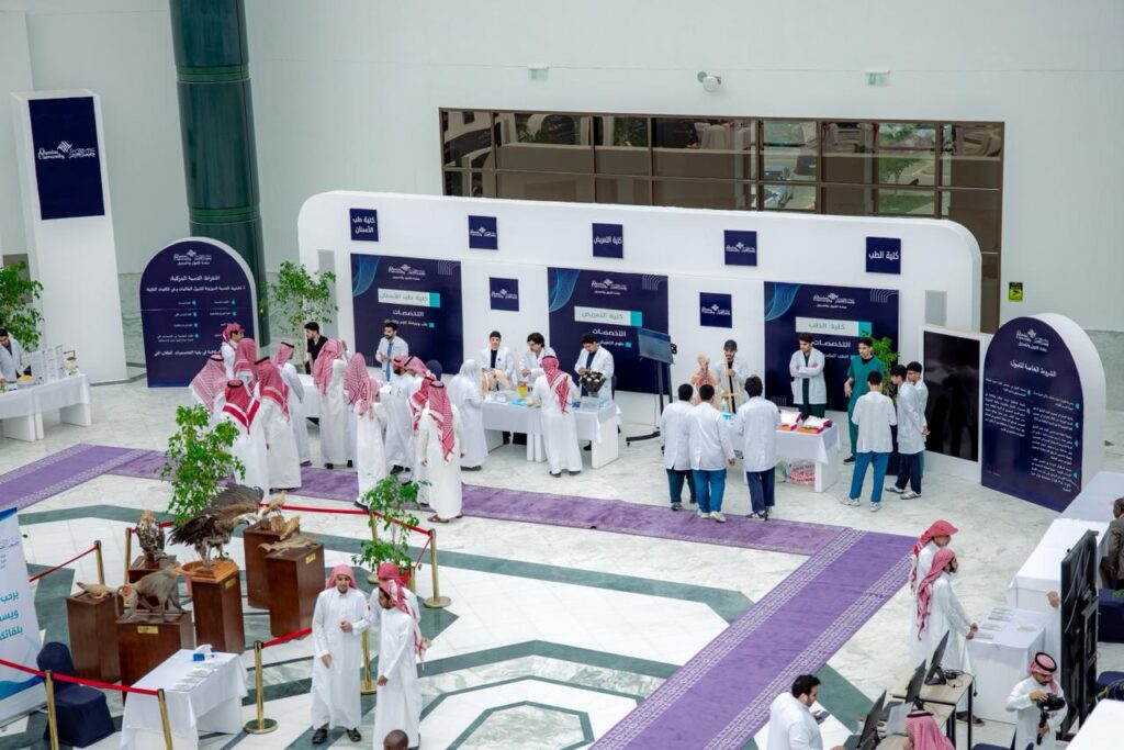 تفاعل رسمي بين الحضور في معرض الطريق إلى الجامعة بجامعة القصيم في قاعة معارض حديثة.