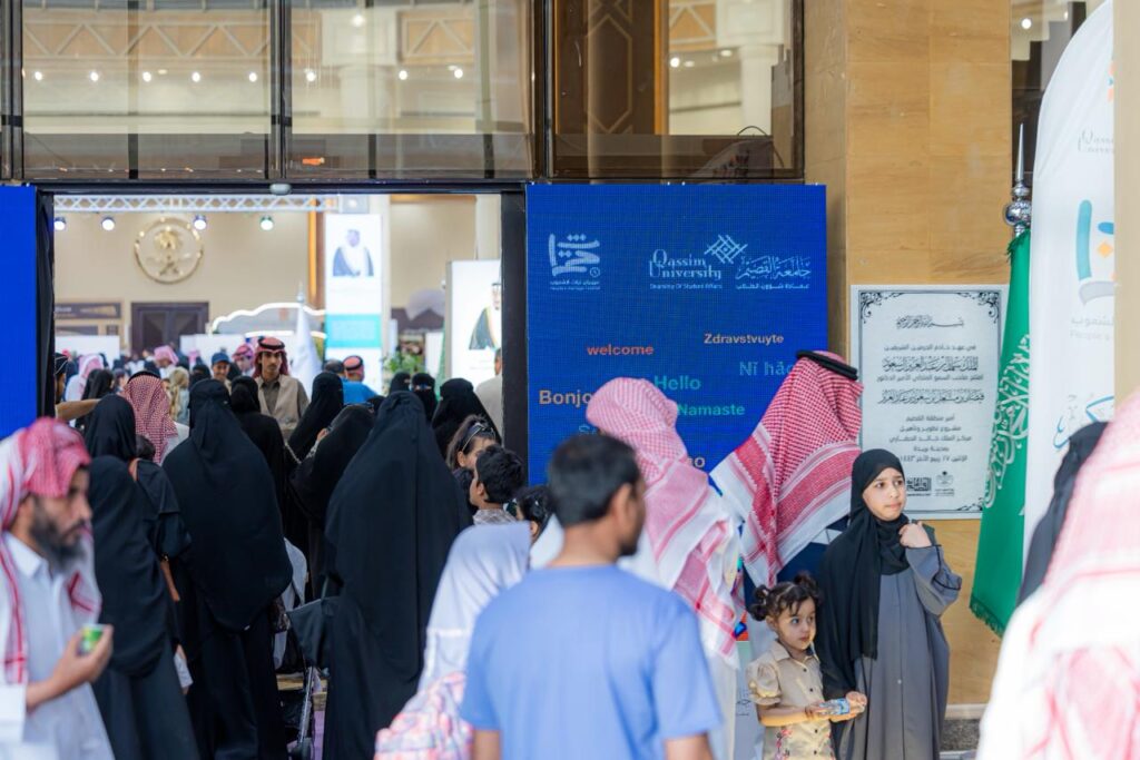 تجمع للزوار أمام مدخل الجامعة في جامعة القصيم في أجواء أكاديمية وطنية.