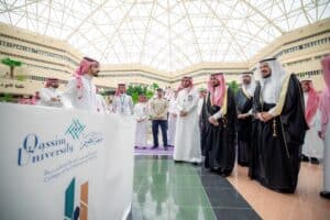 عدد من موظفي جامعة القصيم يتباحثون في قاعة حديثة في إطار فعالية أكاديمية رسمية.