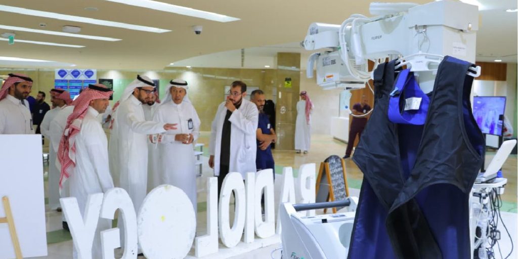 An academic event at Qassim University next to the "Radiology" model and internal medical devices.