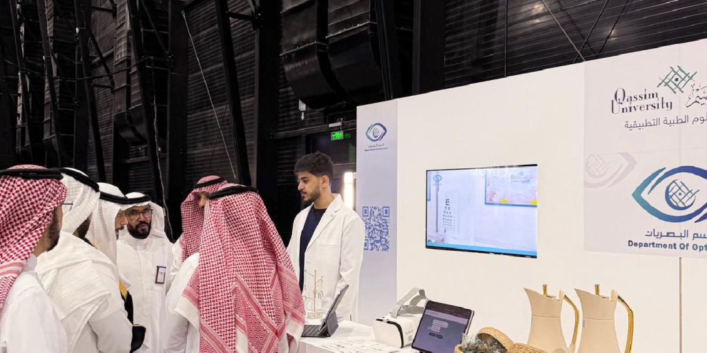 A scientific display at the Qassim University pavilion highlighting optical devices and local crafts at an academic event.
