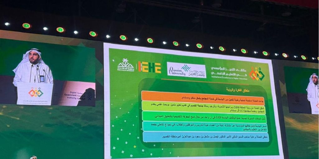 A speaker giving a formal presentation at an academic conference at Qassim University with Arabic text and the conference logo in the background.