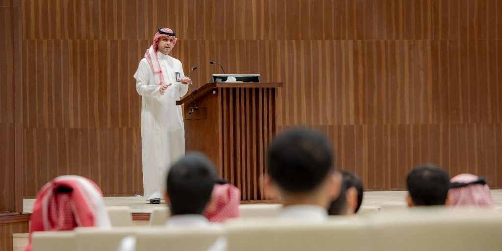 Delivering an academic speech at the Qassim University lecture hall in the presence of a group of interested people.