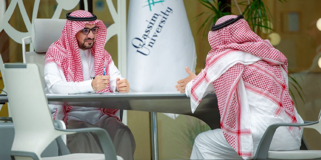 A formal meeting for a member of Qassim University to discuss an academic manuscript in a university setting.