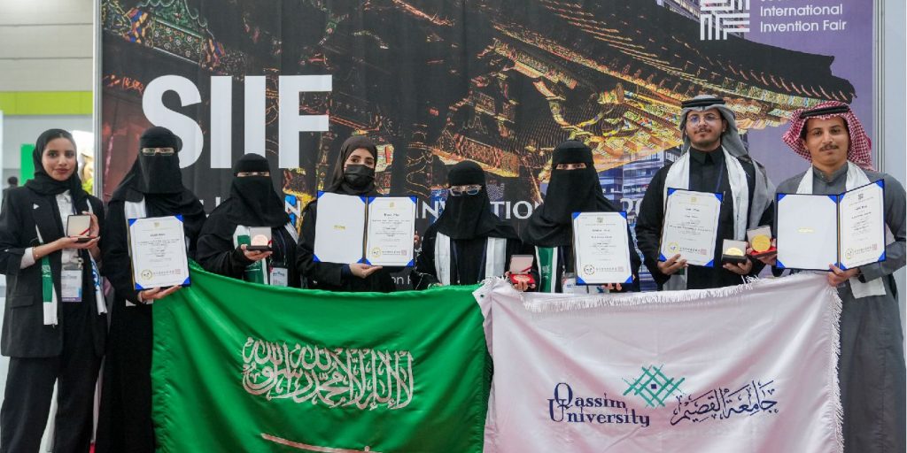 طلاب ومنسوبو جامعة القصيم يرفعون علم الجامعة في معرض سيؤول الدولي للاختراعات.