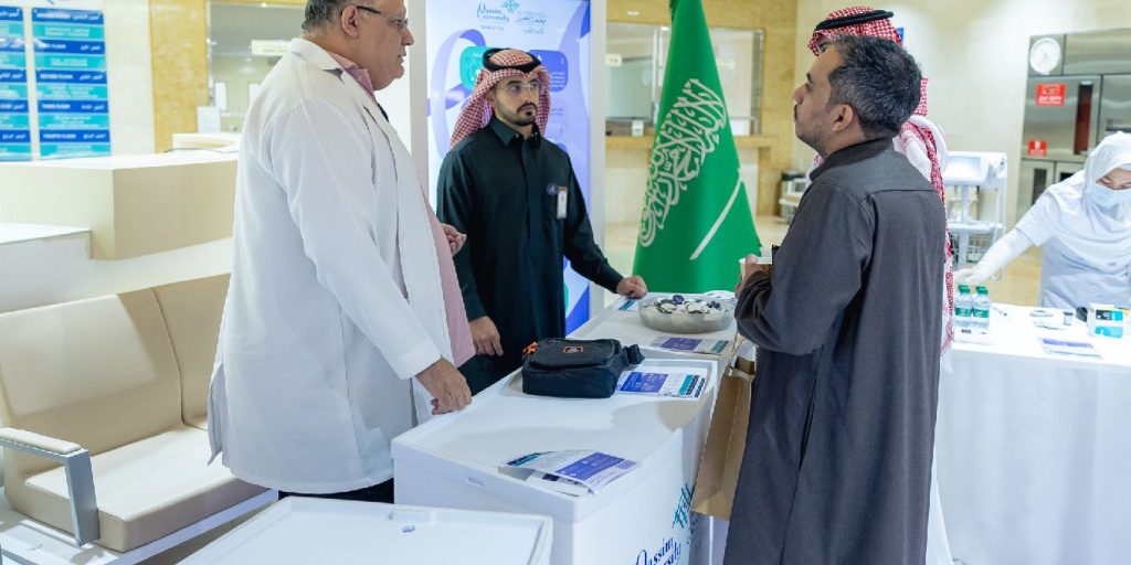 يتكون يتبادلون الحوار في مشاركون في جناح فعالية جامعية بجامعة القصيم مع إبراز هوية وطنية.